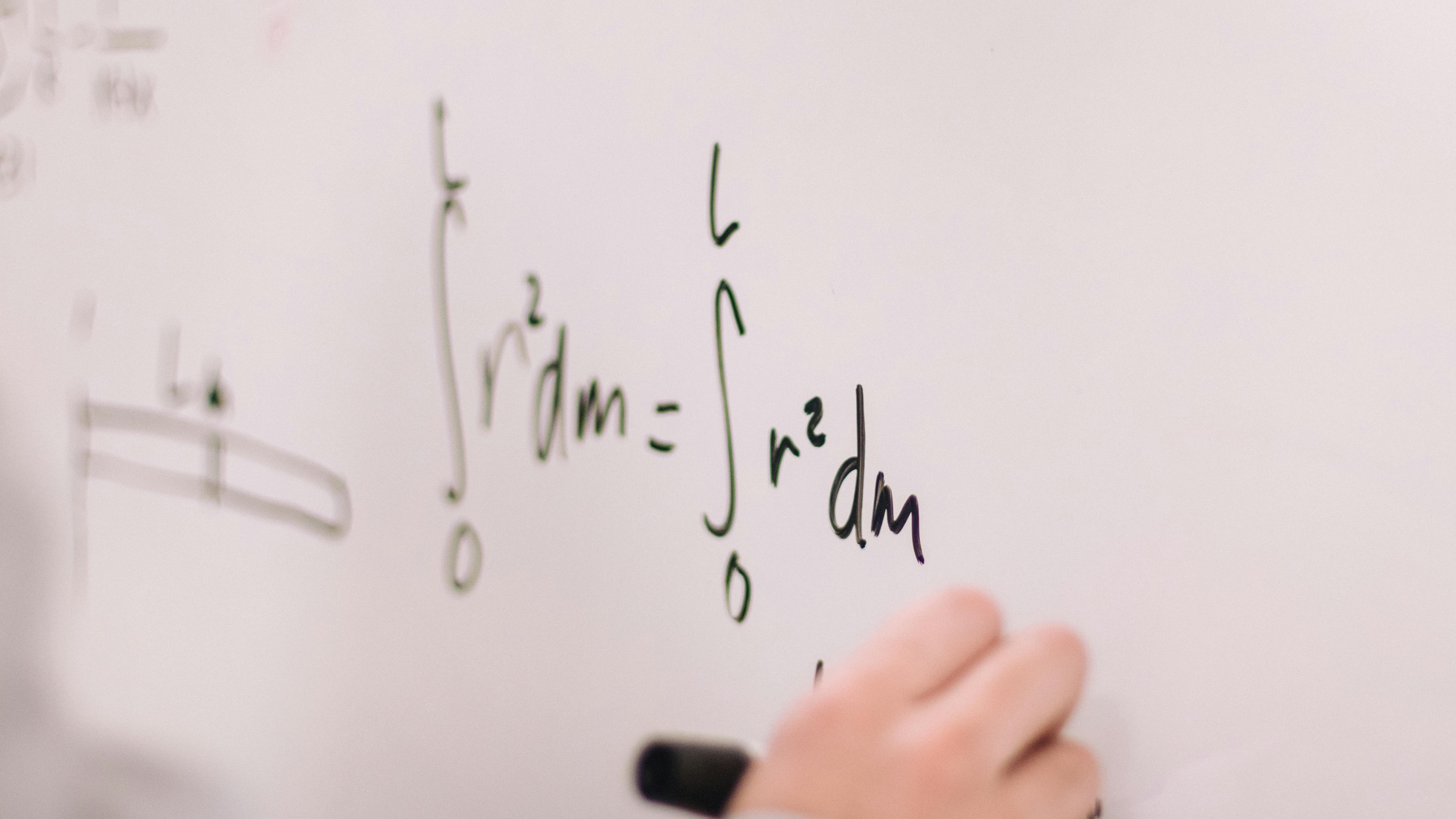 Someone solves a complex math equation on a whiteboard